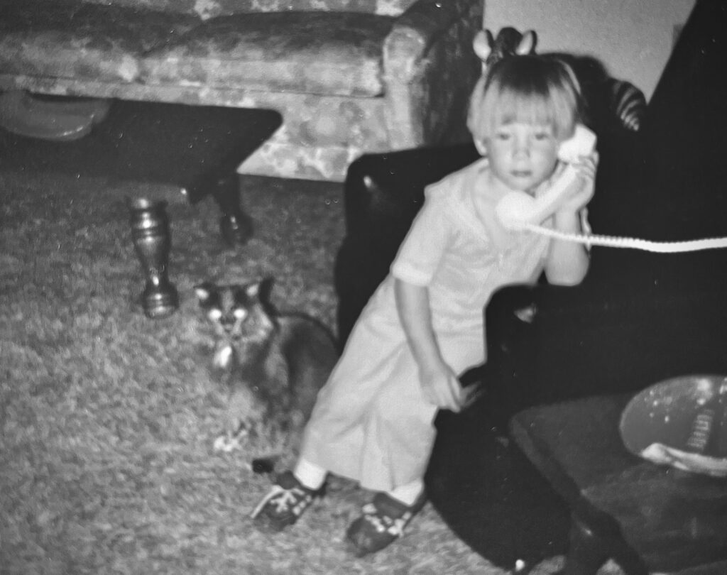 4 year old Brandy talking on the phone with Ranna, her kitty, by her side. Black and white.